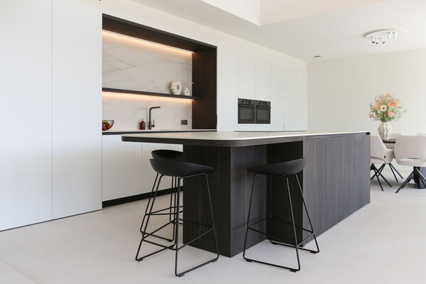 Tijdloze keuken in zwart en wit met marmeren nis en donker houten keukeneiland, realisatie van Ilwa Keukens